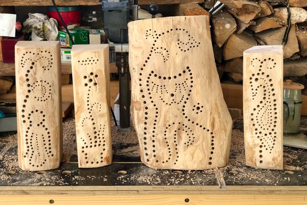 Vier selbstgebaute Nisthilfen aus Holz auf einer Werkbank.