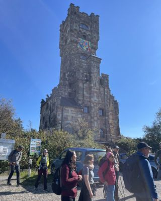 Eine Gruppe wandert an einem Aussichtsturm vorbei.