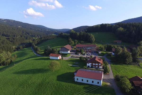 Luftaufnahme des Ortsteils Maierhof mit dem Gasthof Dilger. Die Gebäude liegen idyllisch eingebettet in grüne Wiesen und sind von Wäldern umgeben.