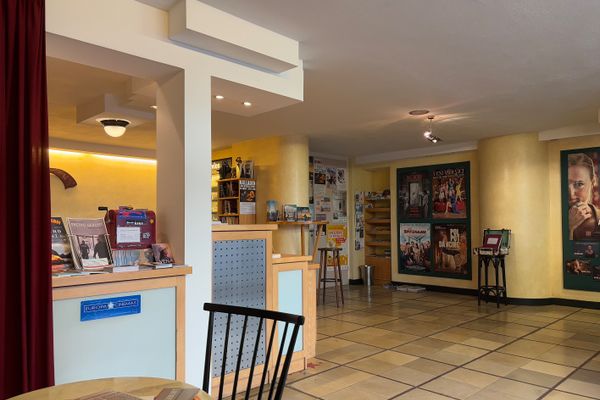 Blick in den Eingangsbereich des Kinos Traumstern mit dem Kartenschalter. An den Wänden hängen Filmplakate und Bistrotische mit Stühlen stehen einladen im Raum.