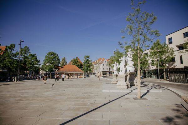 gepflasterter Paradeplatz mit Bäumen und Häusern an der rechten Seite