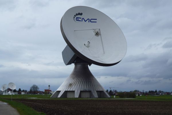 Hinter den riesigen Parabolantennen der Erdfunkstelle wirkt die Raistinger Pfarrkirche St. Remigius vergleichsweise winzig.