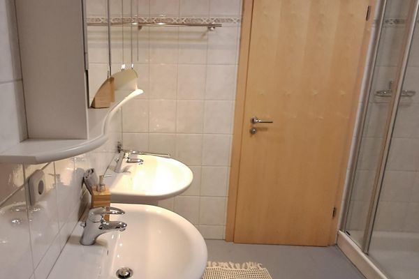 Ausschnitt vom Bad mit zwei weißen Waschbecken, darüber hängt ein Spiegelschrank