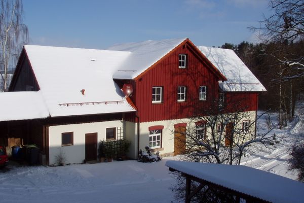 Außenansicht des Ferienhofs im Winter mit weißer Schneelandschaft