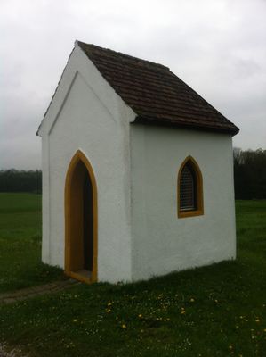 Sehr schlichte weiße Kapelle inmitten einer Wiese.