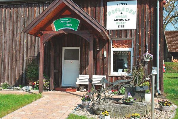 Hofladen Lüters Außenansicht, davor befindet sich ein Blumen Beet mit einer Sitzbank