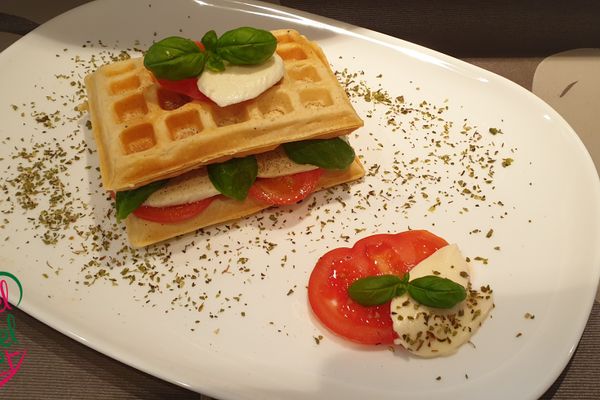 Auf dem Bild ist eine Waffel belegt mit Tomate und Mozzarella zu sehen.