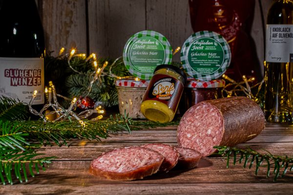 Aufgeschnittene Salami im Hintergrund befinden sich weitere Produkte wie z.B. Öl, Senf oder gekochtes Mett im Glas
