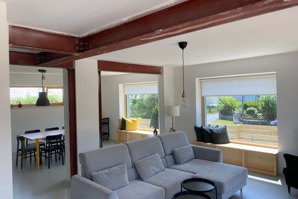 Blick in den lichtdurchfluteten Wohnbereich mit gemütlicher Couch im Vordergrund und Esstisch im Hintergrund