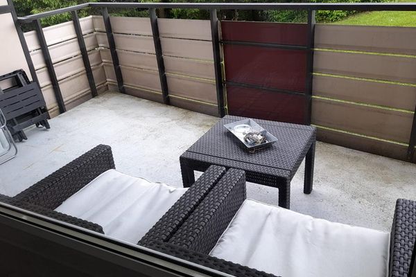 Ein Balkon mit anthrazitfarbenem Geländer und Rattanmöbeln.