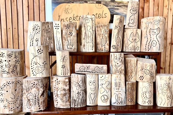 Zahlreiche selbstgebaute Nisthilfen aus Holz stehen auf einem Tisch.