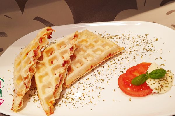 Auf dem Bild ist eine Waffel mit Tomate-Mozzarella Füllung zu sehen.