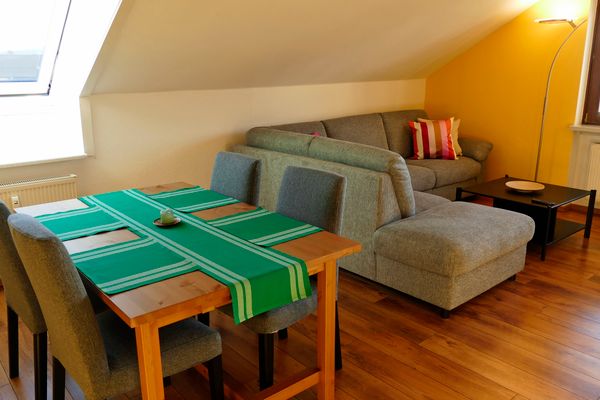 Ferienwohnung Hirtenberg - Wohnzimmer mit Esstisch und Sitzecke im Kissen