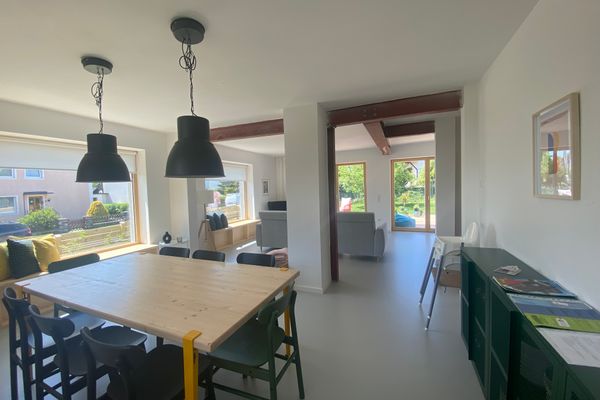 Blick in den Wohn- und Essbereich mit großem Esstisch im Vordergrund und Couch im Hintergrund