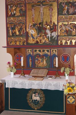 Der Altar in der Martinskirche dort finden zwei Kerzen und die Bibel ihren Platz. Die Abbildung über dem Altar spiegelt die Kreuzigung Jesus wieder, diese ist mit Gold verziert..