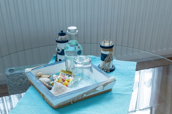 Glastisch mit Tablett, darauf eine Flasche, ein Glas und kleine dekorative Gegenstände