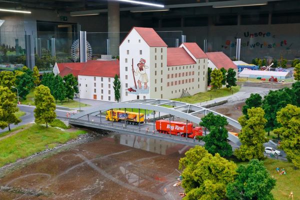 In einer Modelllandschaft fahren zwei Lastwägen über die Straubinger Donaubrücke,  vorbei am Herzogschloß. Im Hintergrund das Gäubodenfest mit Riesenrad.