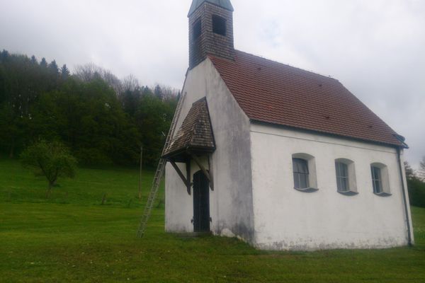 Der Betrachter steht auf einer Wiese und blickt auf eine kleine Kapelle.