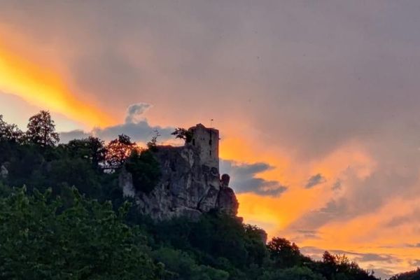 Die Silhouette einer Burgruine im orangen Sonnenuntergang.