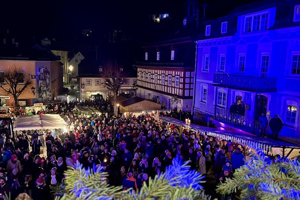 Das Bild zeigt eine Menschenmenge auf einem weihnachtlich beleuchteten Marktplatz