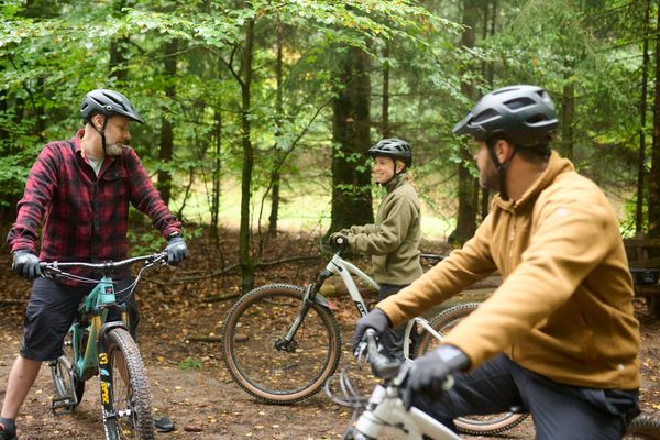 Mountainbiker mit Helm und Ausrüstung fahren auf ihrem Rad eine abgegrenzte Strecke entlang.