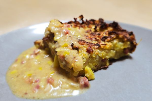 Das Gericht mit Zwiebel-Speck-Sauce liegt auf einem hellblauen Teller in Nahaufnahme vor dem Betrachter.