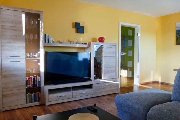 Blick ins Wohnzimmer der Ferienwohnung Hirtenberg auf die Wohnwand mit Flachbildschirm