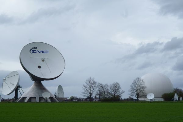 Die übergroßen Antennen der Erdfunkstelle und das Radom vor den Häusern von Raisting.