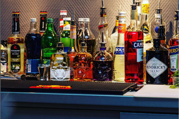 Auf dem Bild sind verschiedene alkoholische Getränke in einem Bar-Ausschank stehend zu sehen. Sie Falschen haben teilweise Ausgießer statt Deckel.
