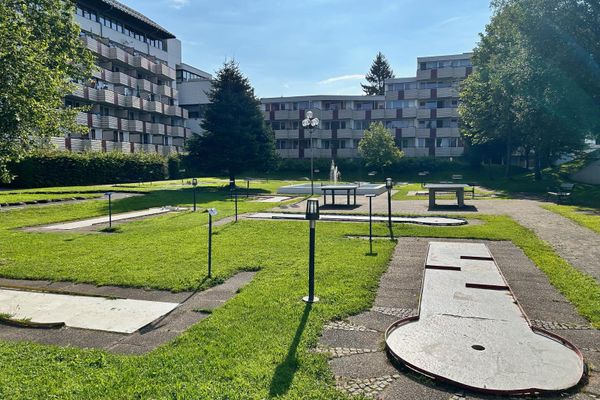 Im sonnigen, teils schattigen Innenhof einer Apartmentanlage befindet sich ein Minigolfplatz mit verschiedenen Stationen.