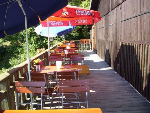Das Bild zeigt die Terrasse der Radspitzalm, es sind Biergartentische und Stühle zu sehen, außerdem Sonnenschirme.