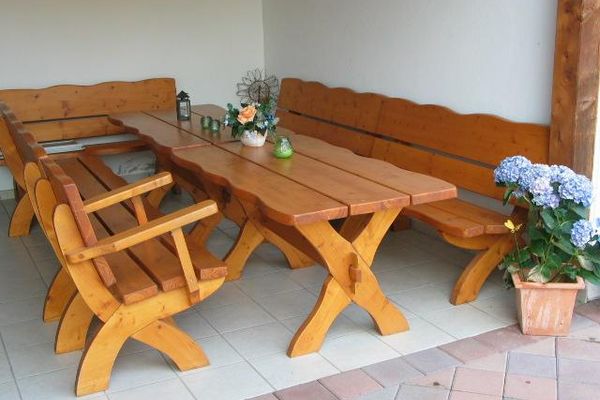 Schöne, stabile Holzbänke und -tische stehen im überdachten Freisitz.