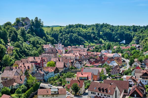Atemberaubender Blick auf die Burg Pottenstein, die hoch über dem Tal thront und das malerische Pottenstein umgibt. Im Vordergrund erstreckt sich eine wunderschöne Ortsansicht des historischen Städtchens mit seinen charmanten Fachwerkhäusern, die dem Ort einen besonderen, traditionellen Charakter verleihen.