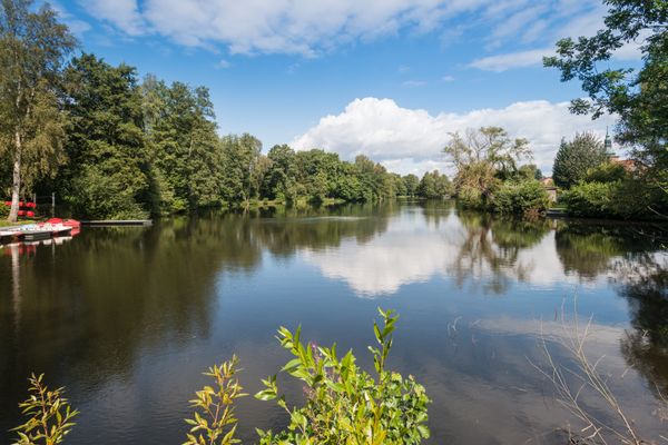Blick über den See, linksseitig mit Tretbootanleger, rechtsseitig mit Kirchturm