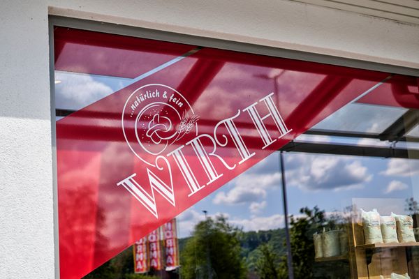 Blick auf das Bäckereilogo, welches auf dem Schaufenster klebt.