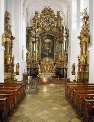Im Mittelpunkt steht der prächtige Hauptaltar der Karmeliten-Klosterkirche in Straubing. Davor, durch ein schmiedeeisernes Gitter geschützt, befindet sich der Zugang zur Gruft. Vor den Seitenaltären sind mehrere Reihen von Kirchenbänken vorhanden.
