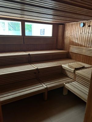 Eine Sauna mit Fenster und übereinanderliegenden, L-förmigen Bankreihen aus Holz.