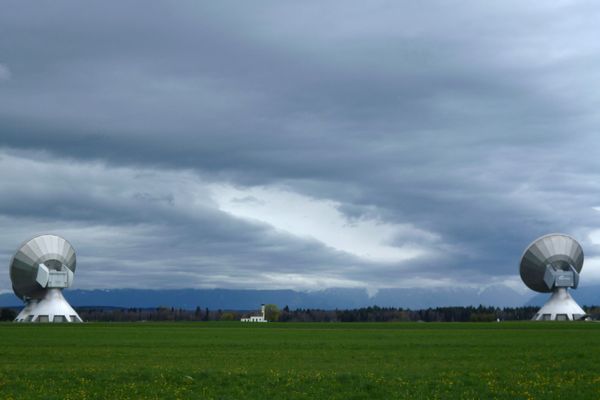 Blick zwischen den riesigen Antennen der Erdfunkstelle hindurch auf die Kapelle St. Johann.