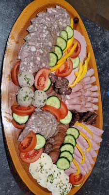 Auf dem Bild ist eine Wurstplatte mit Gemüse dekoriert zu sehen.
