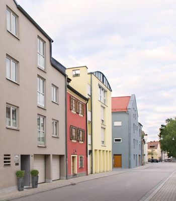 Entlang einer Straße eine Häuserzeile, deren Gebäude in verschiedenen Farben gestrichen sind.