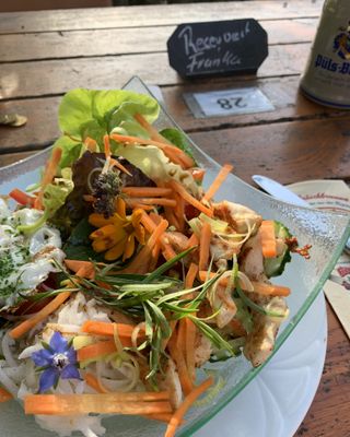 Das Bild zeigt einen Teller mit Salat. Das Gericht ist mit essbaren Borretschblüten dekoriert.
