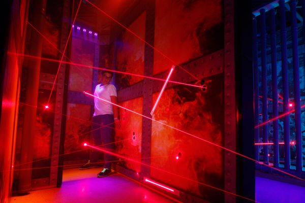 In verschiedenen Schwierigkeitsgraden kämpft sich eine Besucherin durch einen Irrweg aus roten Laserstrahlen.