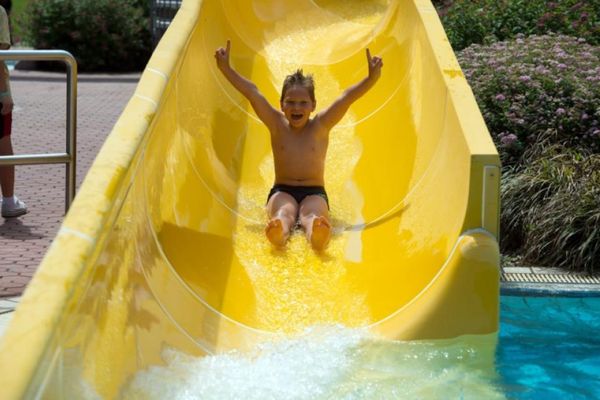 Mit hochgestreckten Armen und lachendem Gesicht geht es auf der Wasserrutsche dem kühlen Nass entgegen.