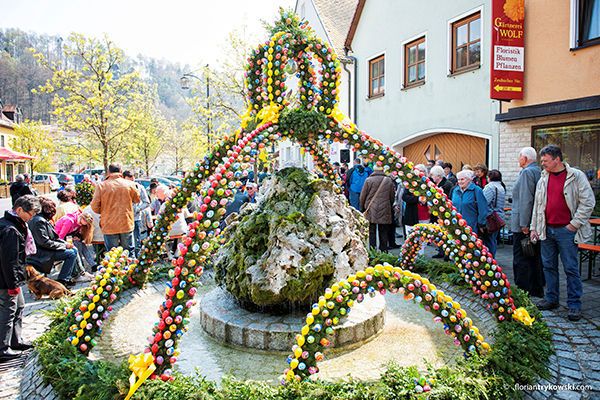 Besucher stehen um einen geschmückten Osterbrunnen.