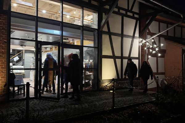 Es ist Nacht und einige Besucher gehen durch die große, gläserne Eingangstür des Schlossmuseums Romrod.