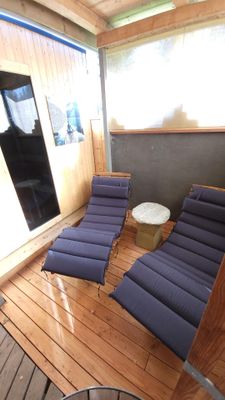 Im Liegebereich vor der Sauna laden zwei Holzliegen mit grauen Auflagen zum Entspannen ein.