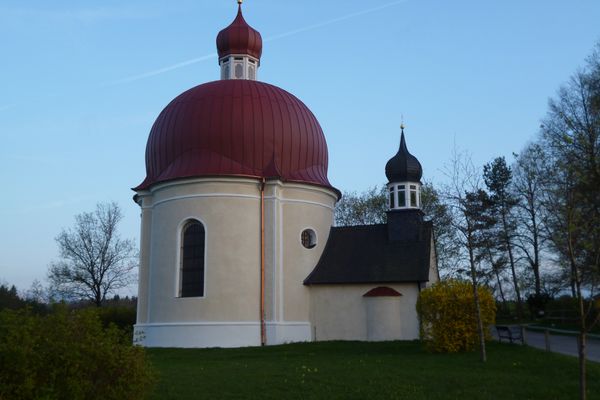 Der originelle Rundbau der Heuwinklkapelle mit dem vorgelagerten Glockenturm thront auf einem Hügel oberhalb von Iffeldorf.