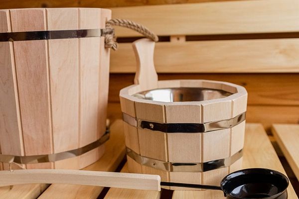 Auf dem Bild sind verschiedene Utensilien für einen Aufguss auf der Bank der Sauna stehend zu sehen.