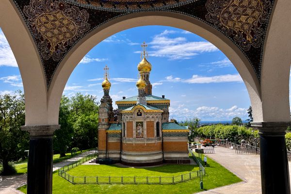 Russische Kapelle mit goldenen Zwiebeltürmen und Mosaikverzierung, gesehen durch einen verzierten Bogenrahmen
