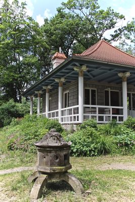 Gebäude das an einen asiatischen Tempel erinnert, dessen Dach geschwungen ist und mit Säulen gehalten wird.